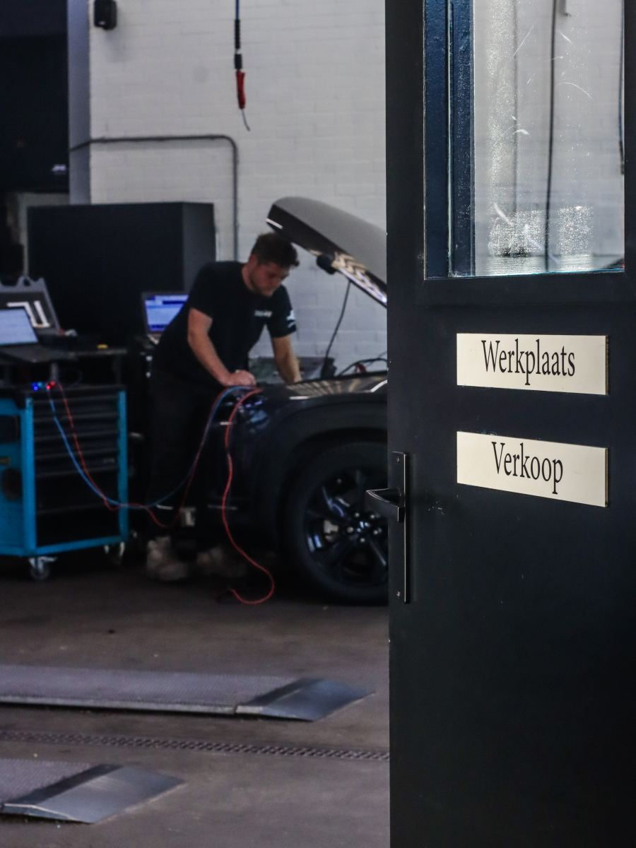 Doorkijk naar de werkplaats van Autobedrijf Overbeek, met de deur naar werkplaats en verkoop